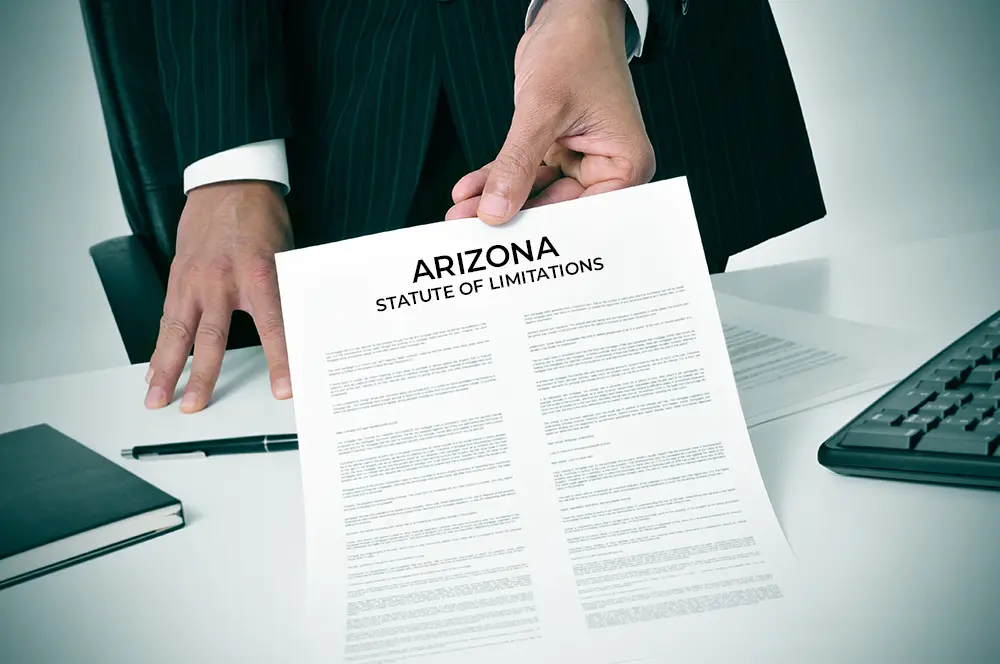 Attorney holding a legal document titled 'Arizona Statute of Limitations,' representing legal guidance after a car accident.
