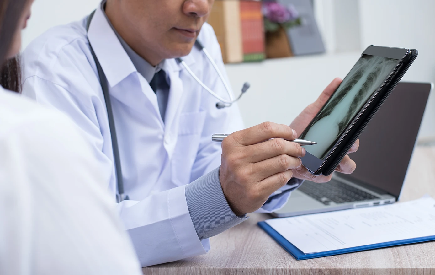 Doctor reviewing chest X-ray results on a digital tablet with a patient after a car accident