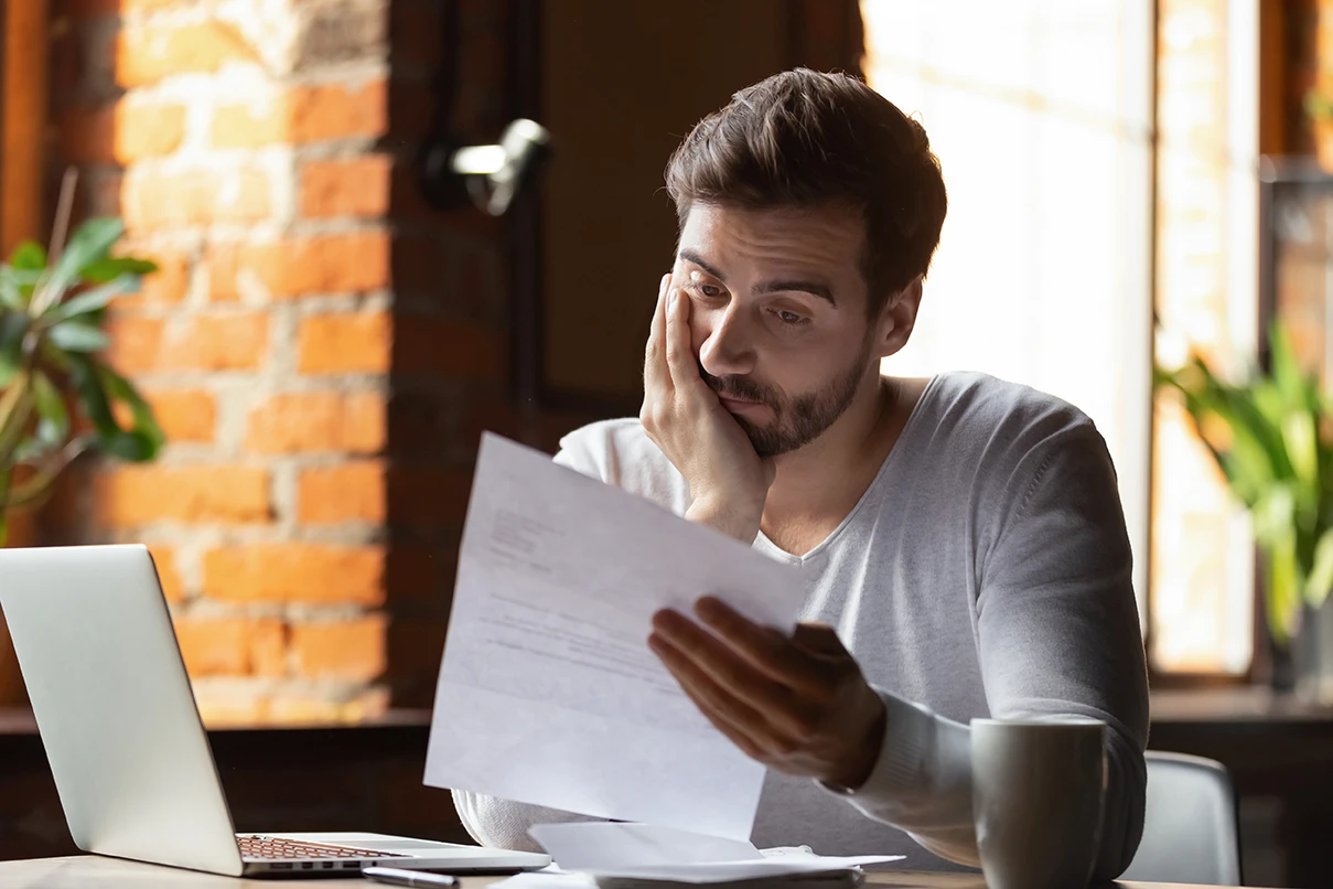 Frustrated man reviewing insurance paperwork after a car accident claim delay
