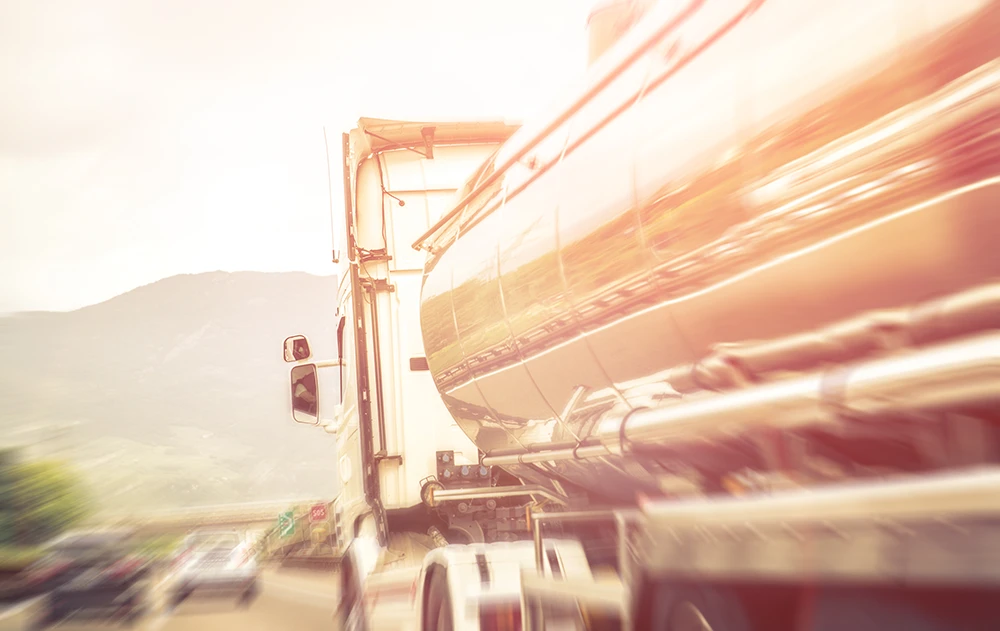 Close-up of a semi-truck driving on an Arizona highway with sunlight reflecting off the trailer