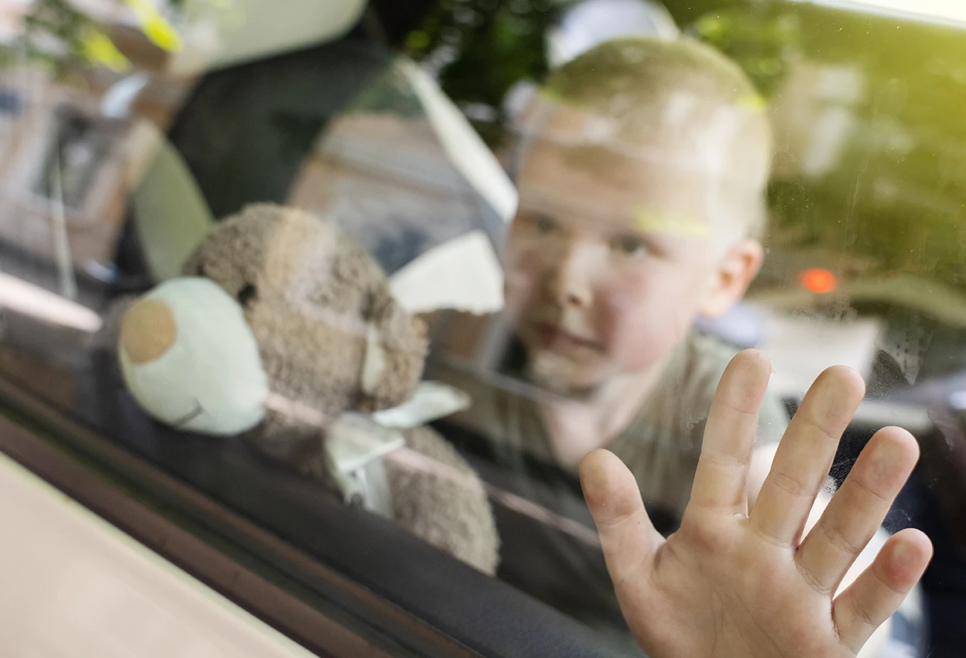 Child looking out car window after being left alone in a hot vehicle in Arizona