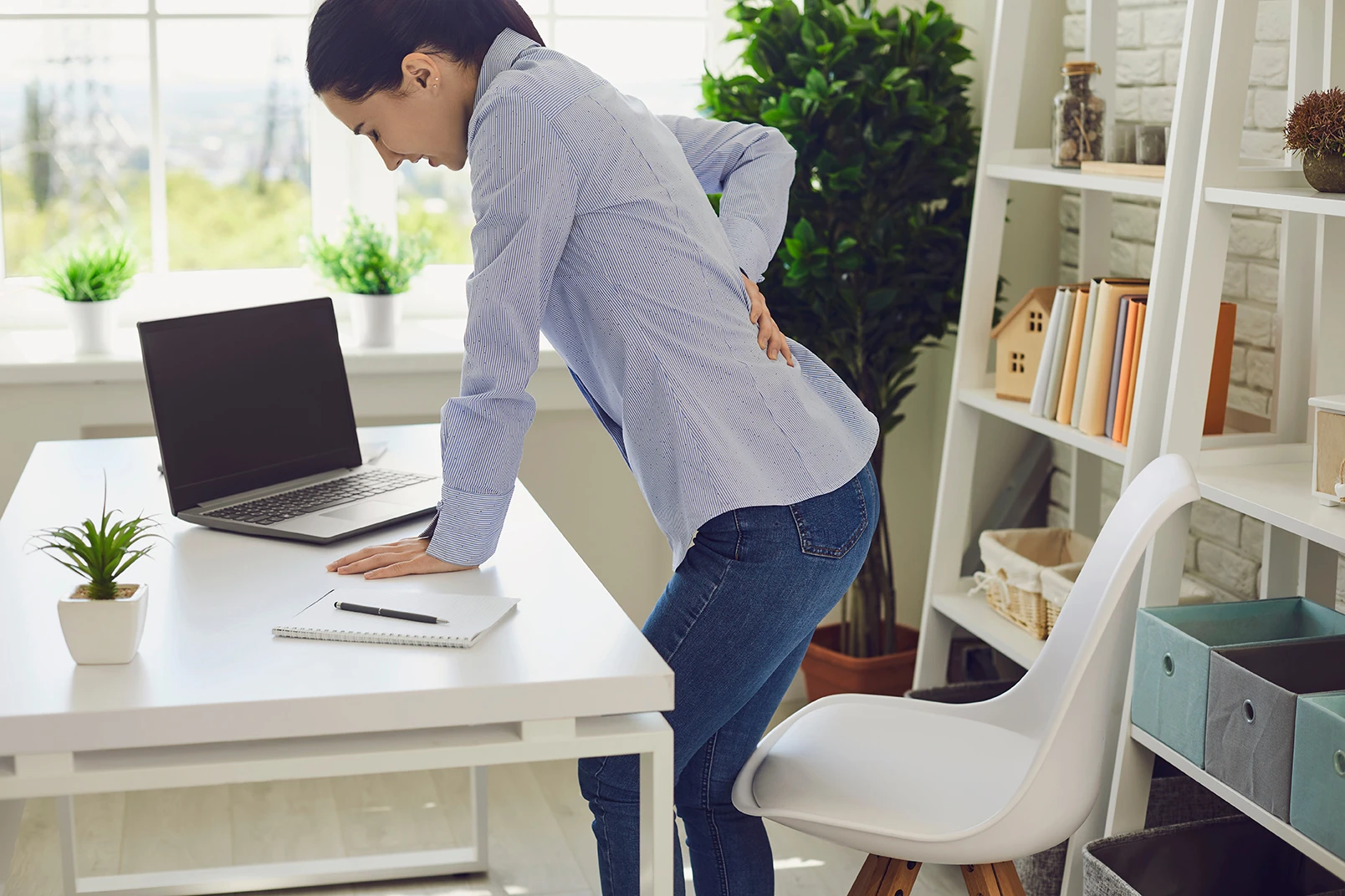 woman experiencing lower back pain while standing at desk after car accident