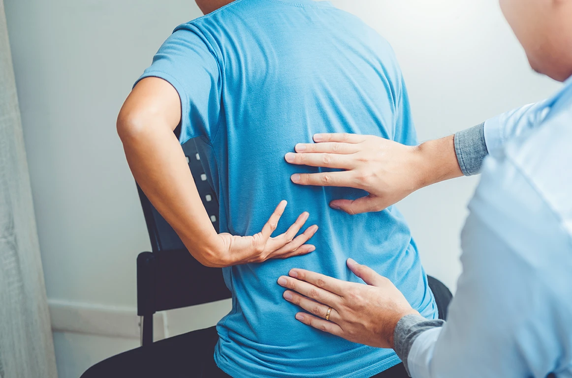 Person experiencing lower back pain during medical examination after a car accident
