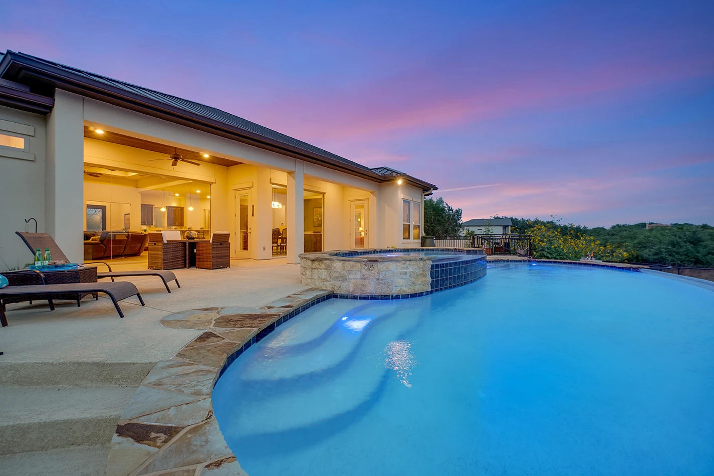 Residential backyard swimming pool at dusk with illuminated water and patio seating, representing pool safety and drowning accident liability.
