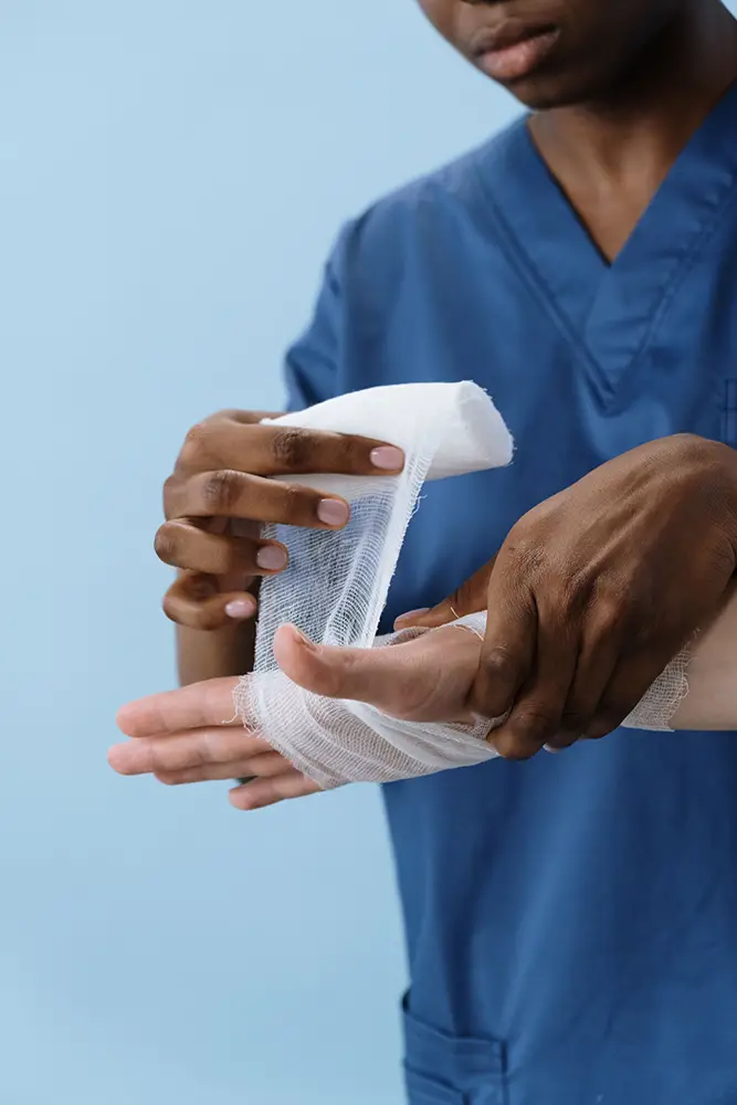 Healthcare professional wrapping a patient’s burned hand with medical gauze