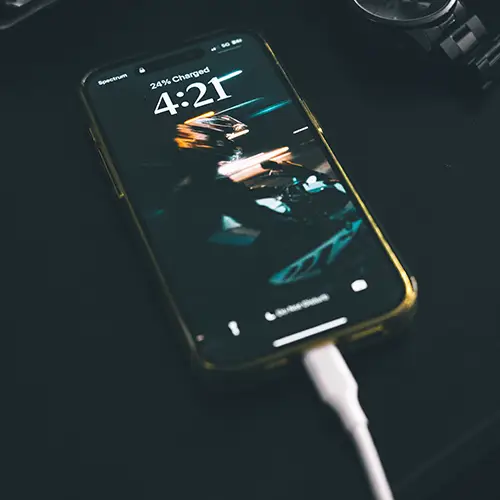 Smartphone connected to a charging cable on a dark surface
