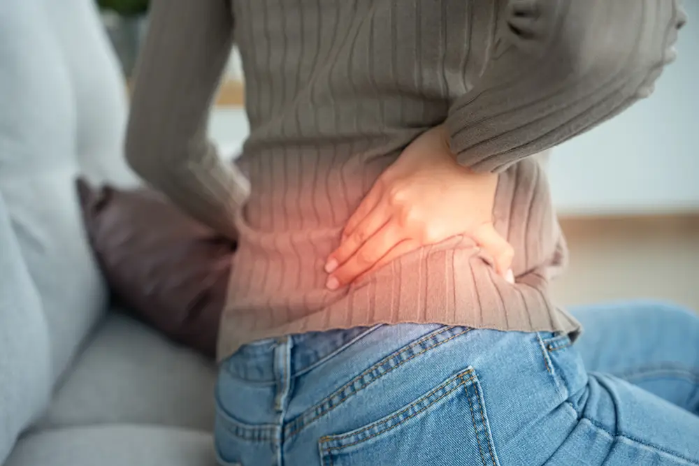 Person holding their lower back due to pain from a possible herniated disc after a minor car accident