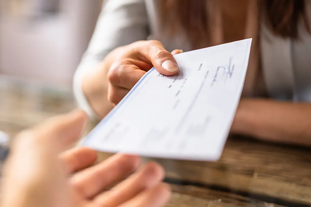 Persona entrega un cheque de indemnización por un accidente automovilístico.