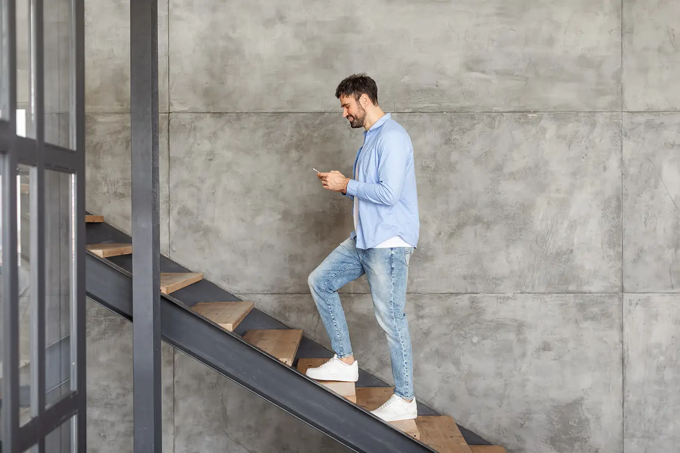 Man looking at his phone while walking on stairs, illustrating distracted walking and slip-and-fall risks