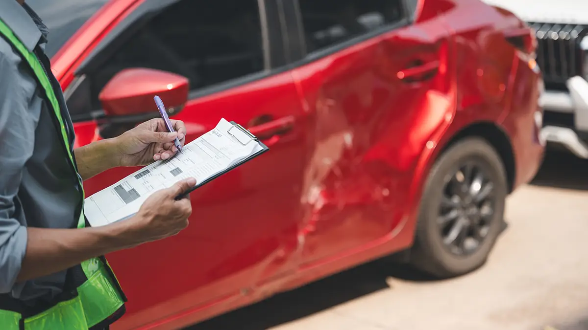 Insurance adjuster documenting damage to a red car after an accident in Arizona.