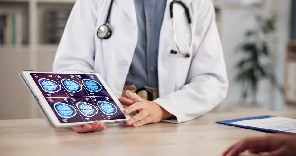 Doctor reviewing a brain scan on a tablet during a medical consultation