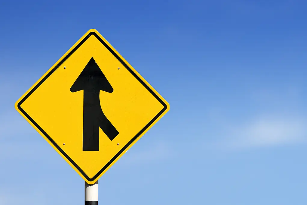 Yellow traffic sign warning drivers of a merging lane on an Arizona roadway.